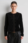 model wearing black leather trousers and a black velvet nepoleon style jacket with a plain background