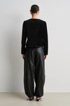 model wearing black leather trousers and a black velvet nepoleon style jacket with a plain background