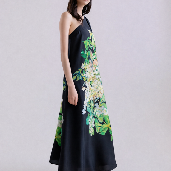 Woman wearing a black silk dress with floral patterns on a plain background