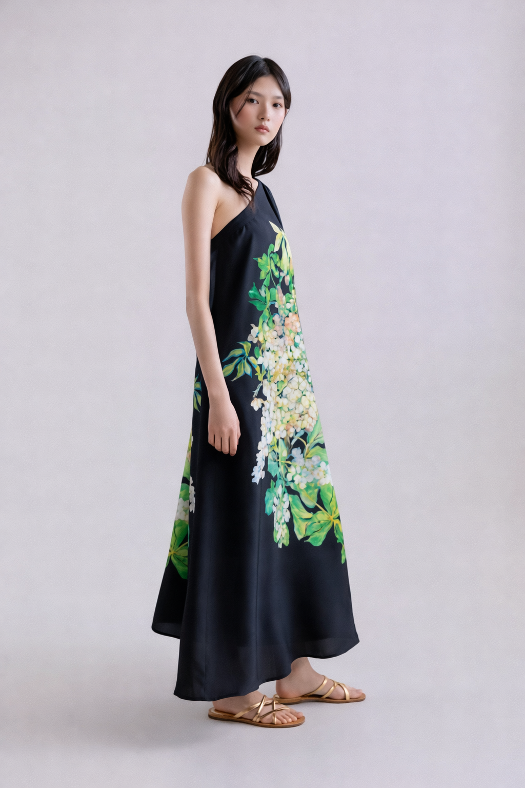 Woman wearing a black silk dress with floral patterns on a plain background