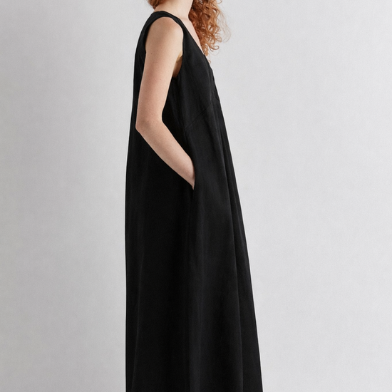 Woman wearing a black sleeveless dress against a plain background