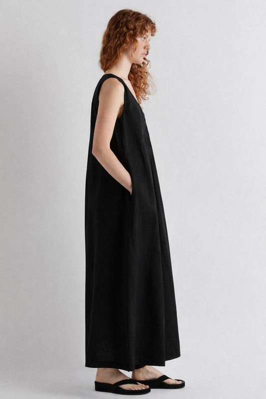 Woman wearing a black sleeveless dress against a plain background