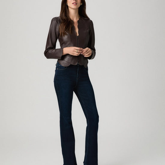 A woman modeling a dark brown satin long-sleeve blouse tucked into dark blue flare jeans with dark brown heeled ankle boots, photographed against a light gray studio background.