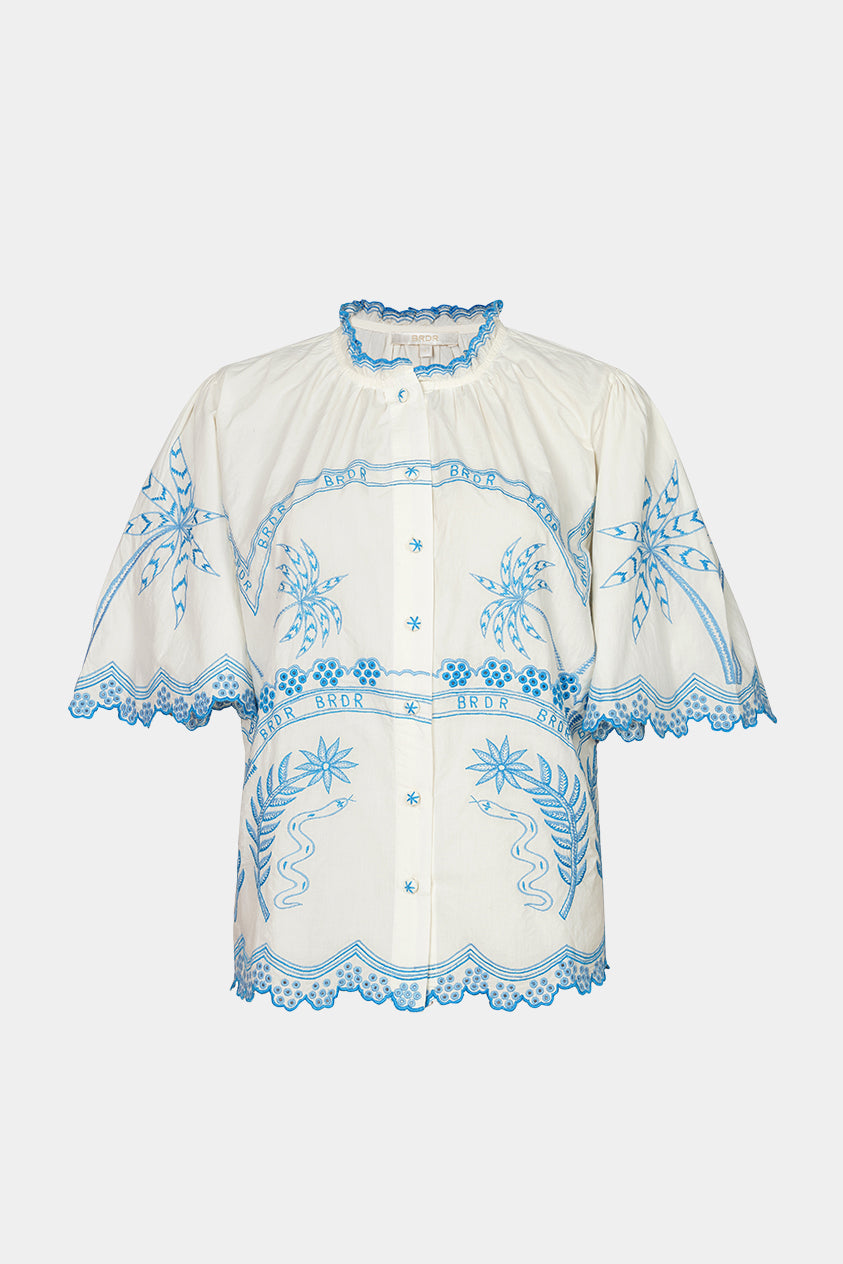 White blouse with blue embroidery on a white background