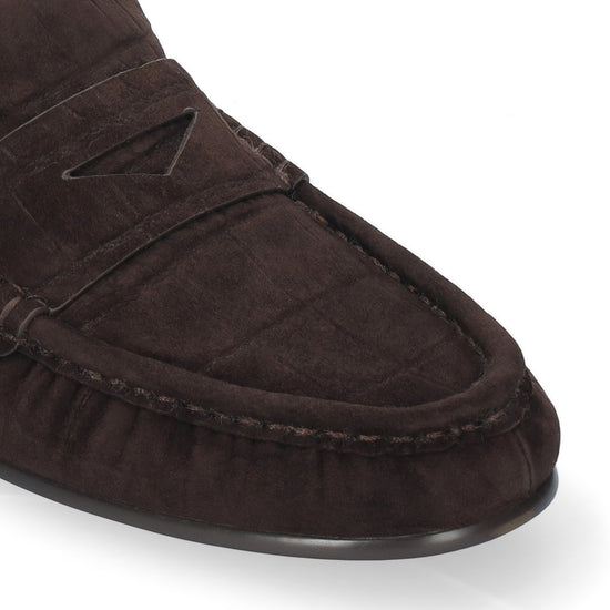 A close-up shot of a dark brown suede moccasin loafer on a clean white background.