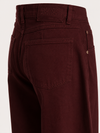 Close-up of the back waistband and rear pocket area of dark burgundy denim jeans, showing the brand label 'ESSENTIEL ANTWERP' and a button closure.