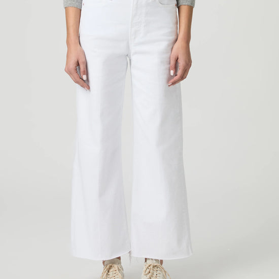 Person wearing white wide-leg paige jeans on a plain background