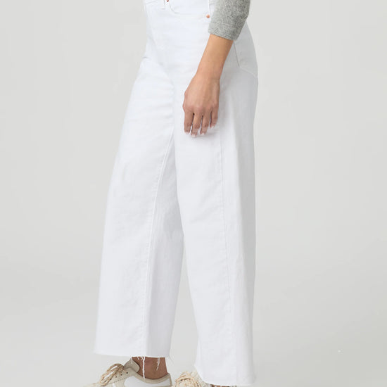 Person wearing white wide-leg paige jeans on a plain background side view