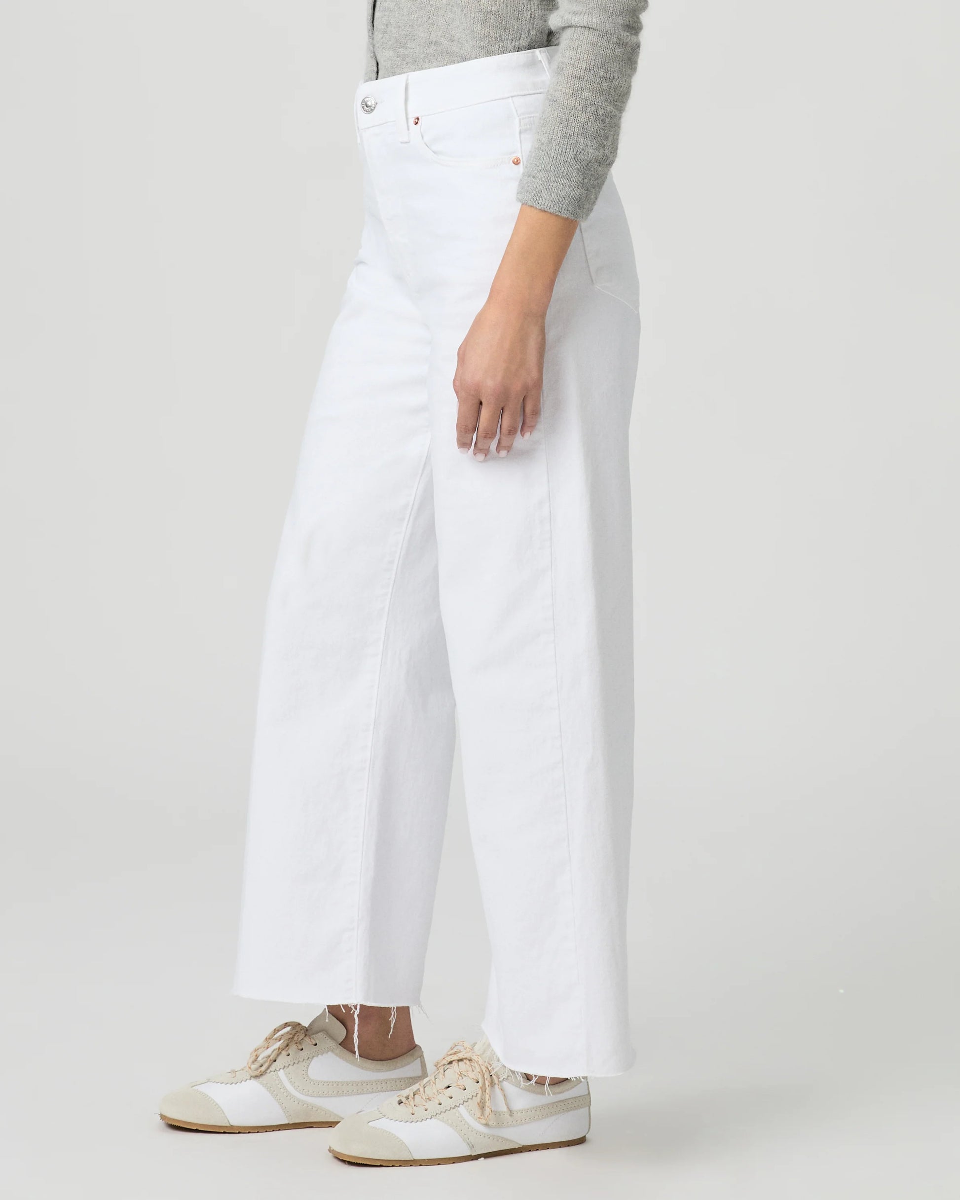 Person wearing white wide-leg paige jeans on a plain background side view