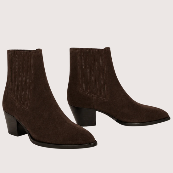 A pair of dark brown suede ankle boots with ribbed elastic side panels and low block heels, displayed against a solid light beige background.