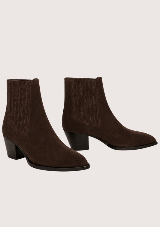 A pair of dark brown suede ankle boots with ribbed elastic side panels and low block heels, displayed against a solid light beige background.