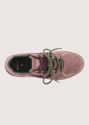 A top-down view of a pink suede sneaker with olive green laces and a black interior, shown on a light beige background.