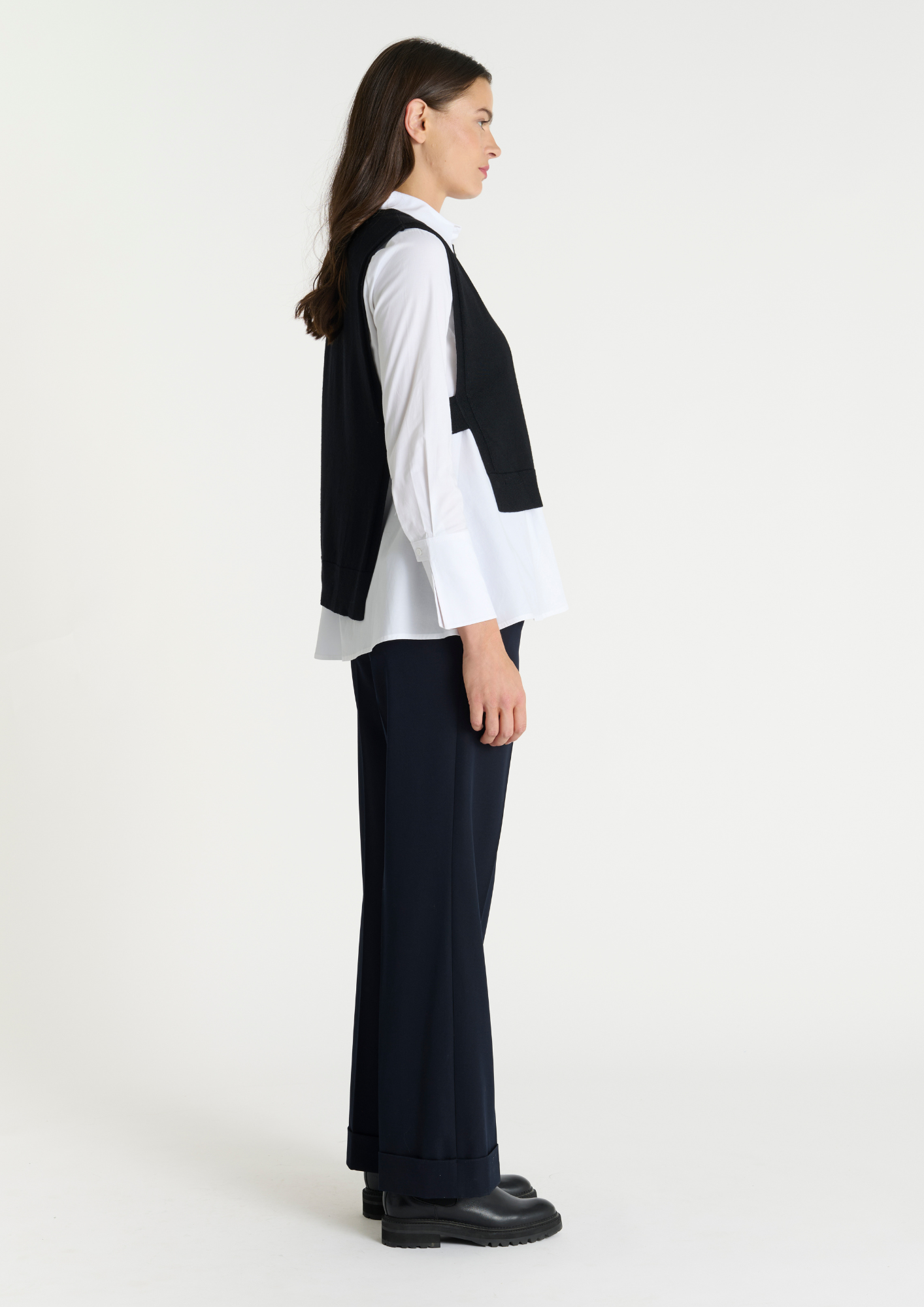 Black pullover vest with ribbed neck knit. Side view.