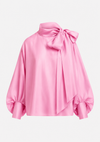 A pink satin blouse with a large bow at the high neck, balloon sleeves, and gathered cuffs, shown on a plain light gray background.