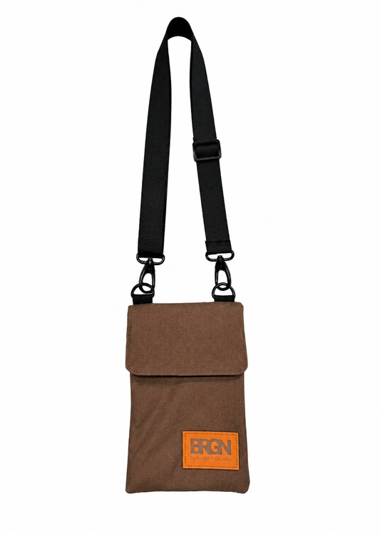 A brown canvas crossbody pouch bag with a black adjustable shoulder strap and a bright orange rectangular logo patch on the front flap. The brand name 'BRGN' is printed in black on the orange patch.
