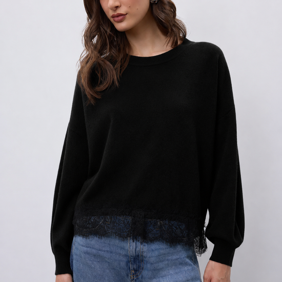model wearing a black crew neckline knit with lace hem and blue jeans 