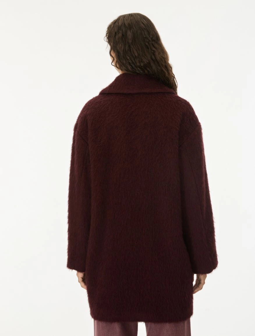 A model shown from the back wearing a textured, fuzzy dark burgundy coat against a plain white background.