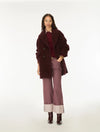 A model stands against a plain white studio background wearing a dark burgundy fuzzy double-breasted coat over a burgundy top, paired with dusty mauve wide-leg jeans featuring light beige turned-up cuffs and dark brown boots.