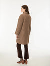 A woman shown from the back wearing a brown and beige houndstooth patterned coat, dark brown cropped trousers, and brown leather block-heel mules, photographed against a clean white studio background.