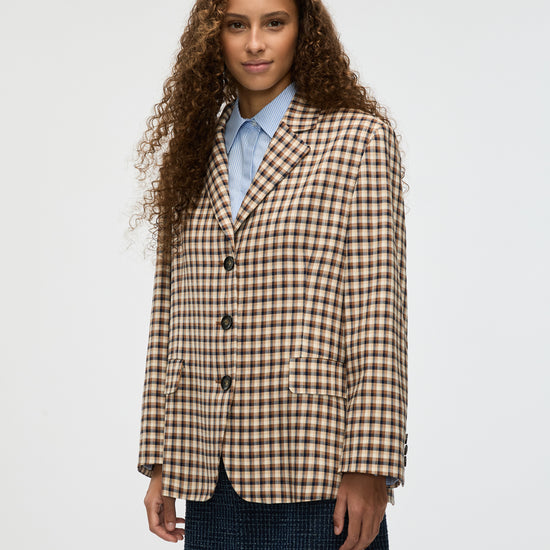 Woman wearing a checkered blazer and blue shirt on a white background