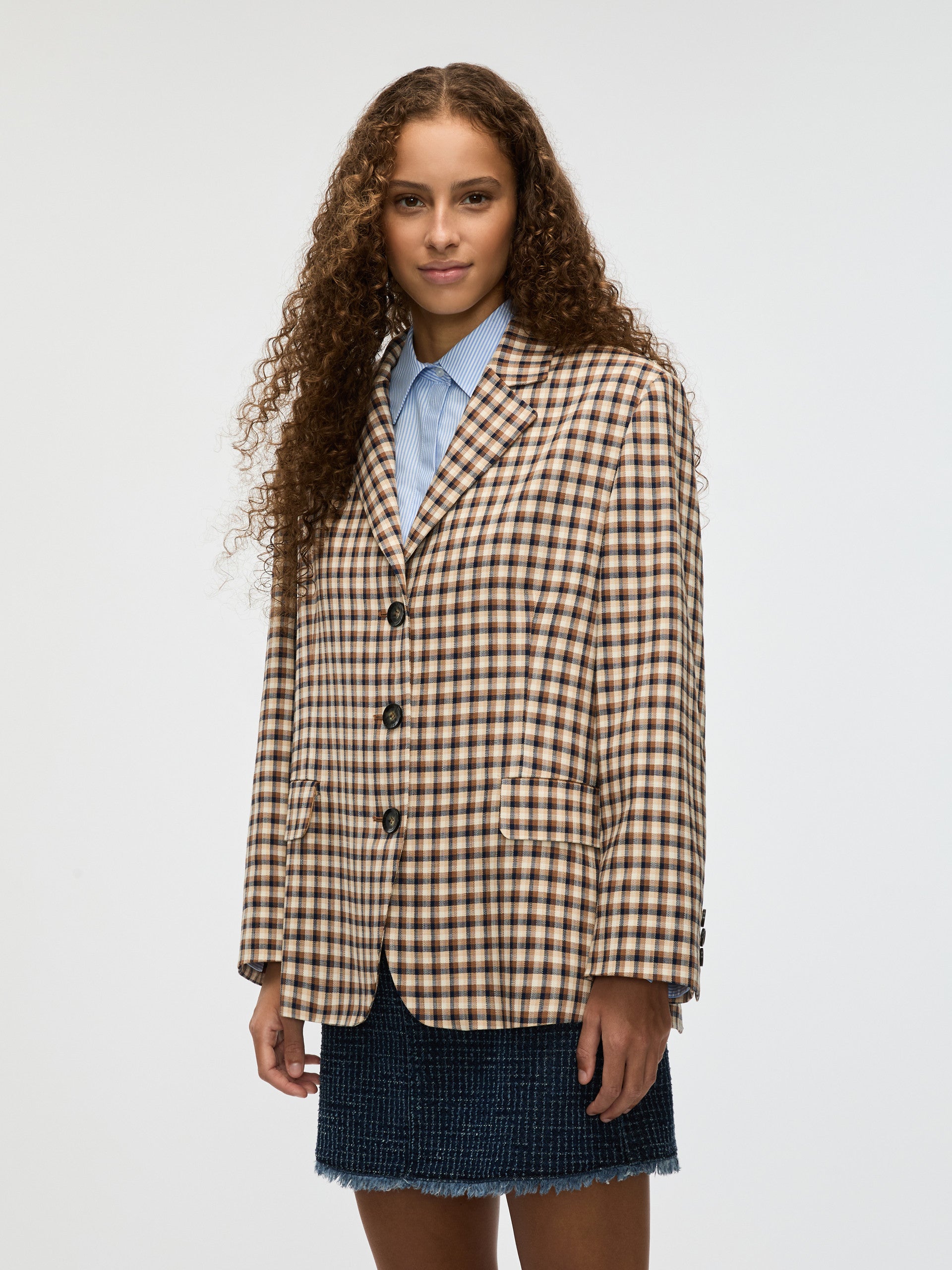 Woman wearing a checkered blazer and blue shirt on a white background