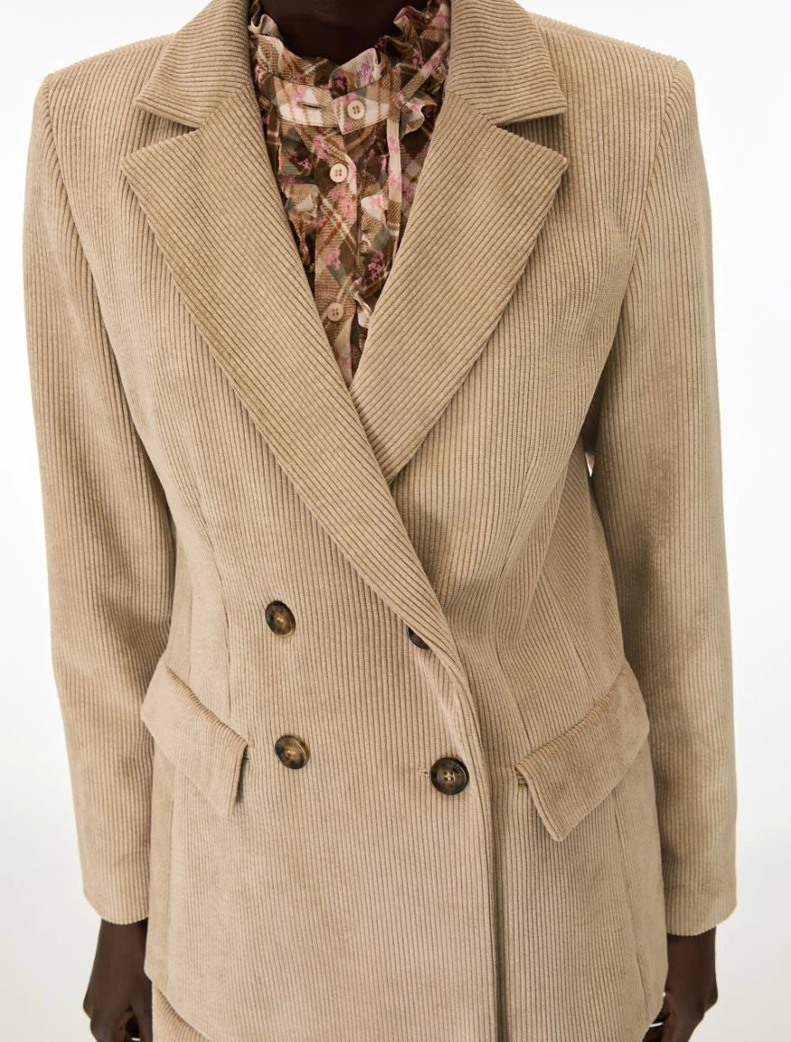 A beige corduroy double-breasted blazer with dark brown buttons, worn over a floral print shirt, shown on a mannequin against a plain white background.