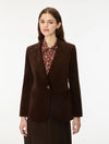 A woman modeling a dark brown corduroy blazer over a patterned collared blouse and dark skirt, photographed against a clean white studio background.
