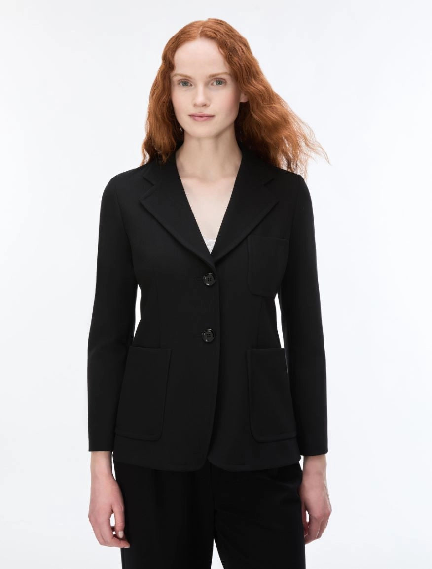 A woman with red hair wearing a black tailored blazer with notch lapels, two front buttons, and flap pockets, photographed against a clean white studio background.