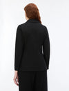 A woman with red hair is shown from the back wearing a black long-sleeve blazer and matching black trousers against a plain white studio background.