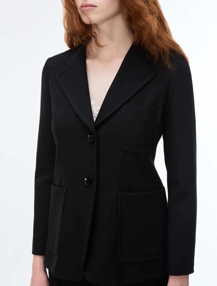 A woman wearing a tailored black blazer with notch lapels, two front buttons, flap pockets, and a structured silhouette, shown against a plain light background.