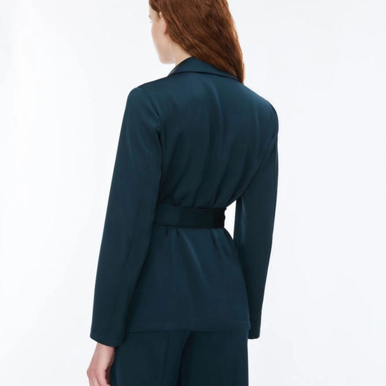 Woman wearing dark teal blazer and trousers rear view