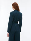 Woman wearing dark teal blazer and trousers rear view