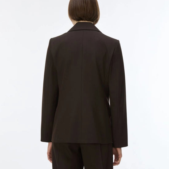 A model viewed from the back wearing a dark brown tailored blazer and matching trousers against a plain white studio background.