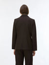 A model viewed from the back wearing a dark brown tailored blazer and matching trousers against a plain white studio background.