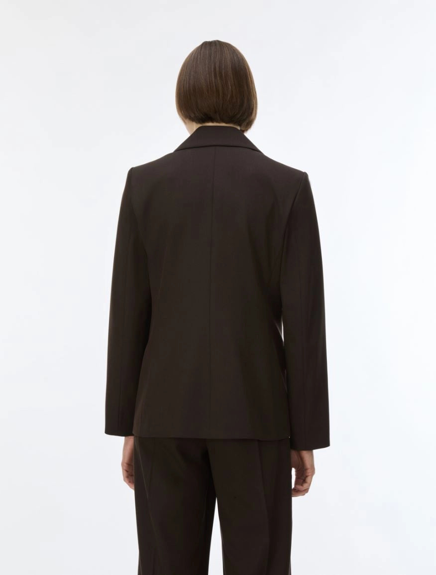A model viewed from the back wearing a dark brown tailored blazer and matching trousers against a plain white studio background.