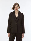 A woman modeling a dark brown tailored blazer with matching trousers against a plain light gray studio background.