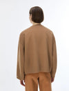 A model shown from the back wearing a camel brown knit cardigan and matching brown trousers against a plain white studio background.