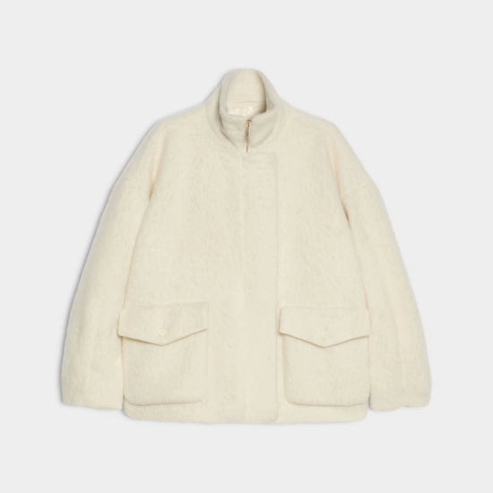 An off-white textured fleece jacket with a stand-up collar, front zipper, and two large flap pockets, shown against a light gray background.