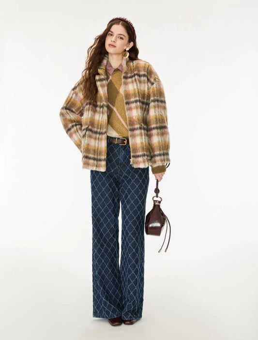A woman models a stylish outfit featuring a beige and brown plaid fuzzy jacket, a tan knit sweater, dark blue patterned wide-leg trousers, and a small dark brown handbag, set against a plain white studio background.
