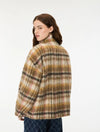 A woman wearing a fuzzy plaid jacket in beige, brown, and black, photographed from the back against a plain white studio background.