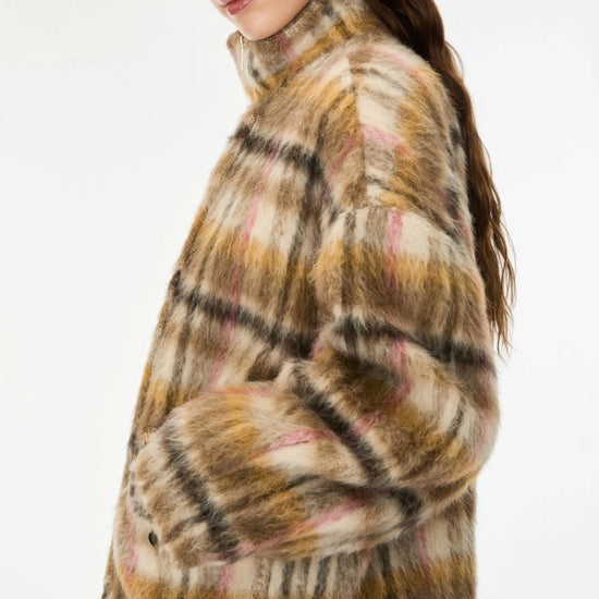 woman wearing khaki and pink check coat on a white background side view