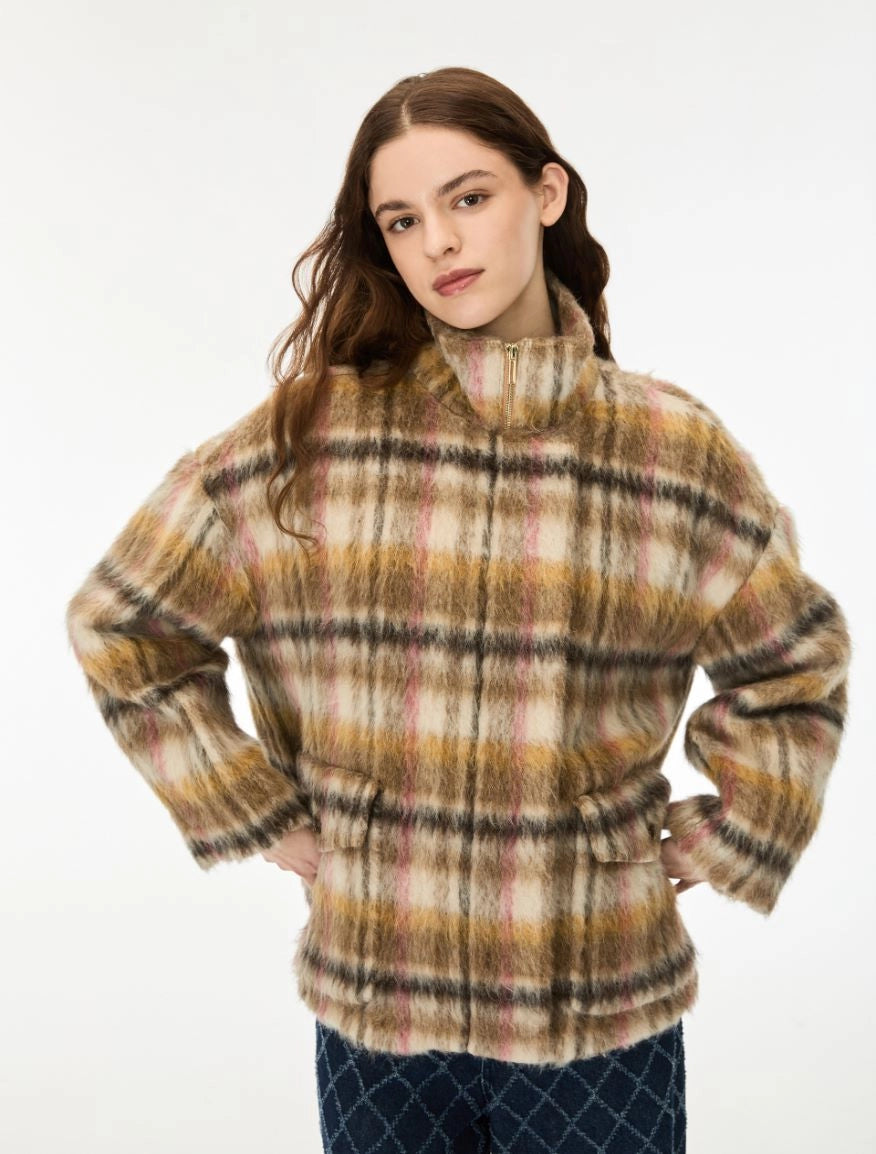 A woman modeling a fuzzy, long-sleeve plaid jacket with a mock neck and tie waist, in a beige, brown, and yellow plaid pattern, against a plain white background.