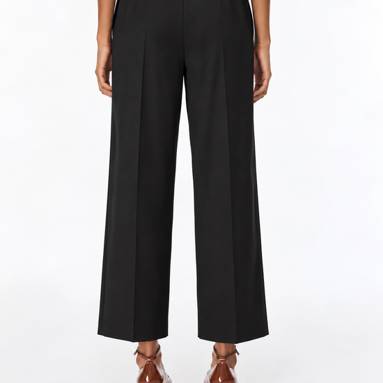 A model shown from the back wearing black wide-leg cropped trousers, a light beige top, and brown leather block-heel mules against a plain white studio background.