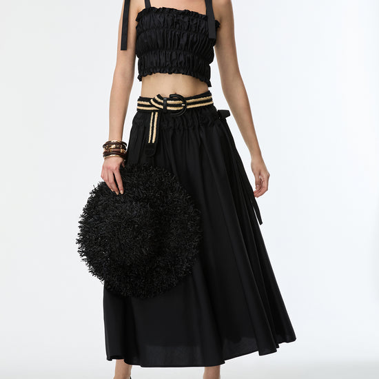 Woman wearing a black outfit with a textured skirt and top on a white background
