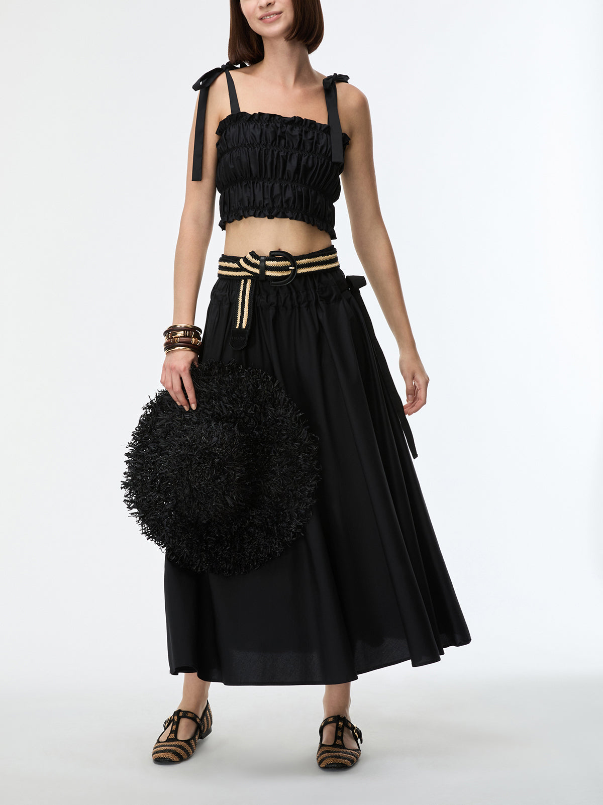 Woman wearing a black outfit with a textured skirt and top on a white background