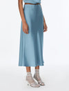A model wearing a light blue satin midi skirt with a matching top and sheer high-heeled sandals, shown from the waist down on a white studio background.