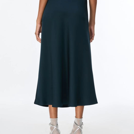 woman wearing teal blue skirt with silver heels rear view