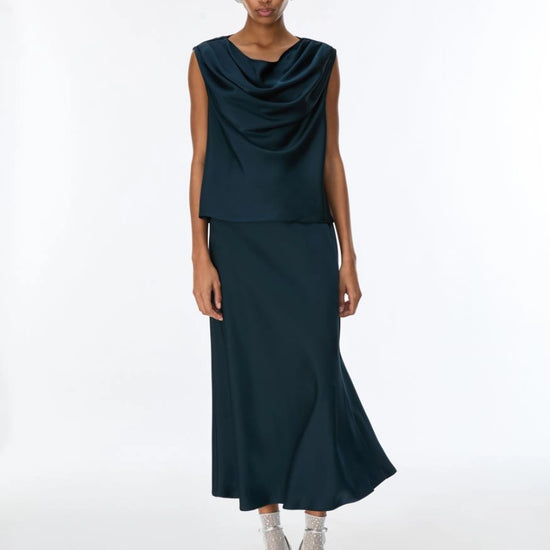 Woman wearing a dark green sleeveless top and skirt set on a white background