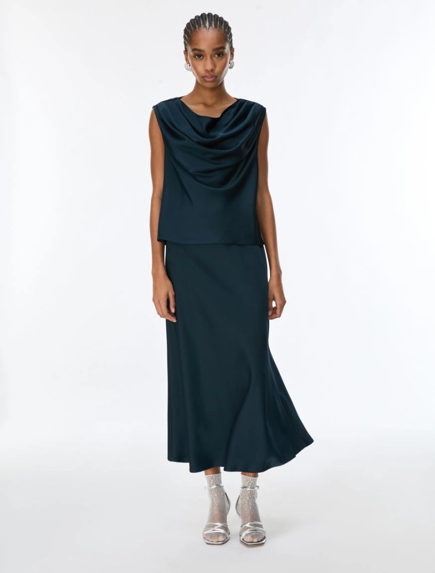 Woman wearing a dark green sleeveless top and skirt set on a white background
