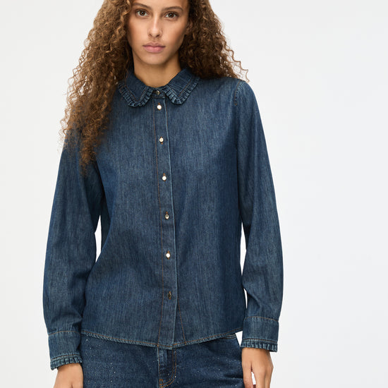 Woman wearing a blue denim shirt and pants on a white background